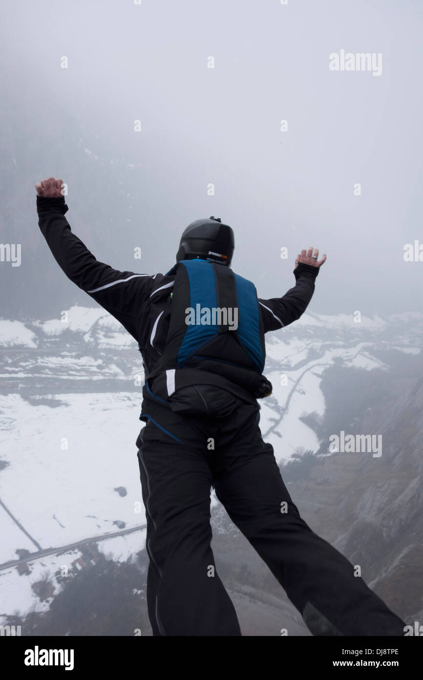 Base-Jumper wird von einer Klippe hinunter in das tiefe Tal beendet. Damit hält er seine Arme sich stabil sein und sparen. Stockfoto