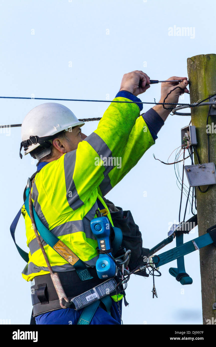 Telefon-Ingenieur auf einem Telegrafenmast Befestigung Telefonleitungen. Stockfoto
