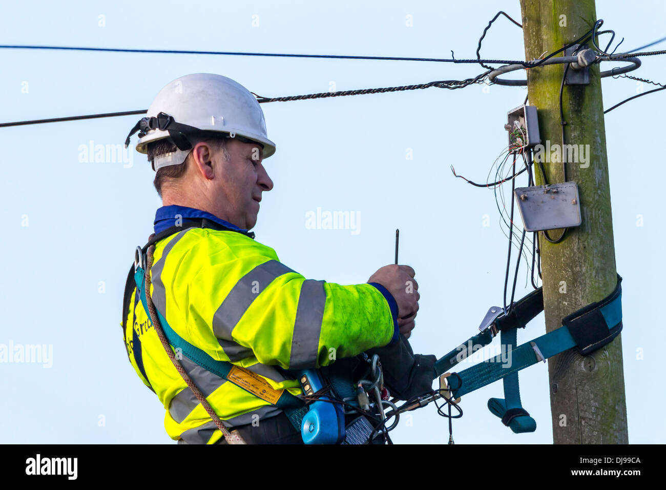 Telefon-Ingenieur auf einem Telegrafenmast Befestigung Telefonleitungen. Stockfoto