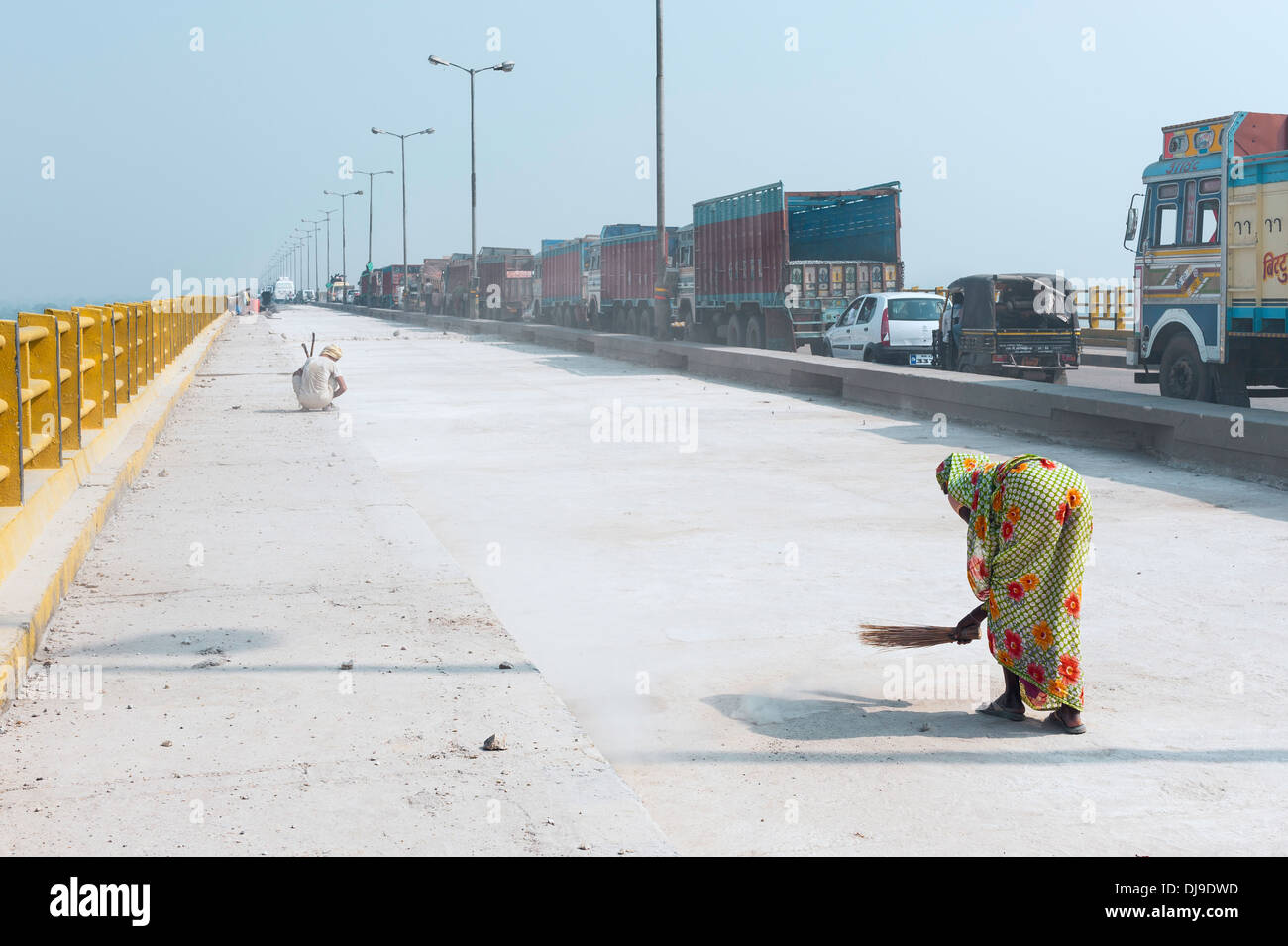 Frau mit Hand Besen fegt die Mahatma Gandhi Setu (Brücke) bei der Renovierung und ein sehr langer Stau. Stockfoto