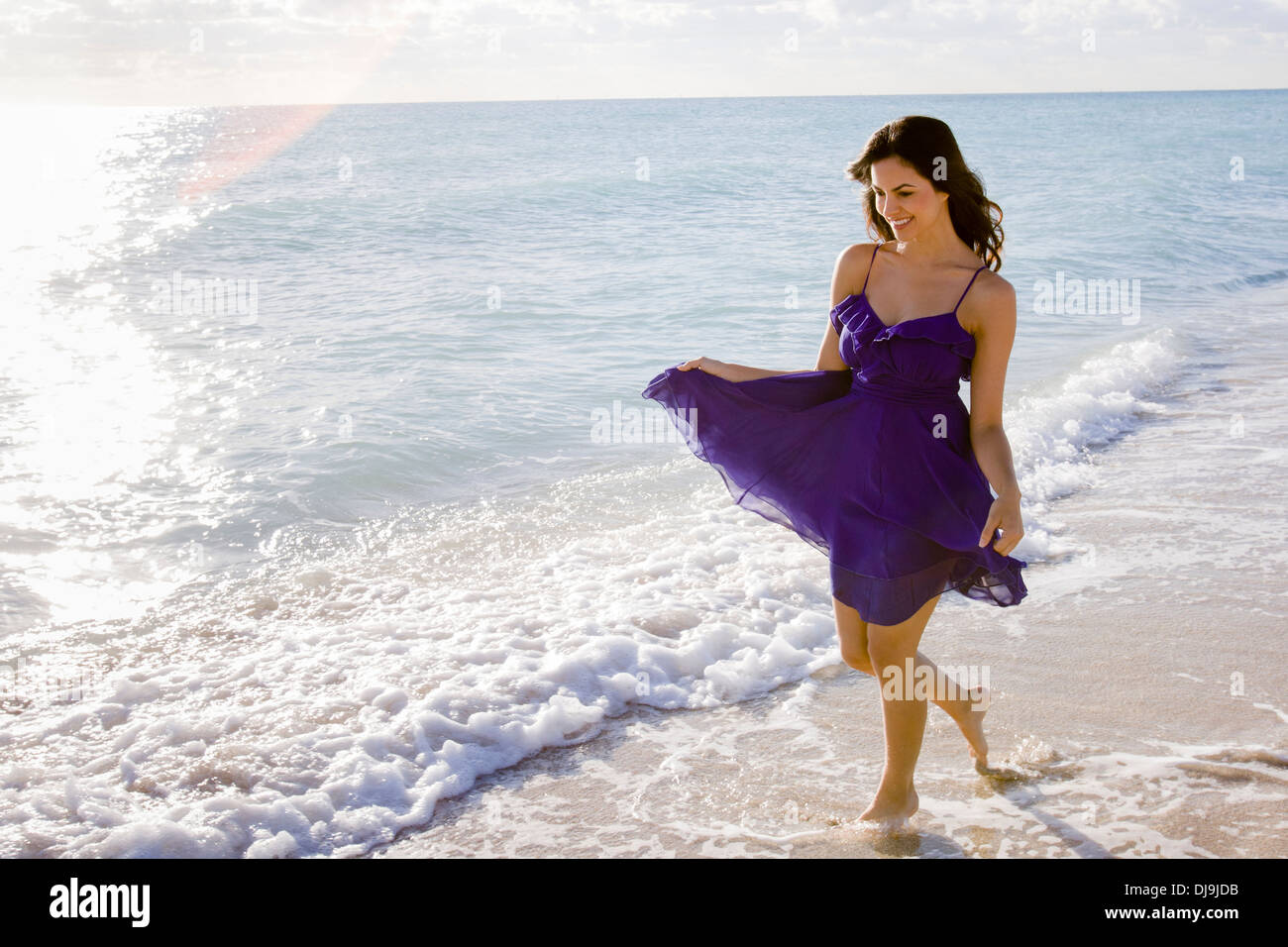 Hispanic Frau zu Fuß in Brandung am Strand Stockfoto