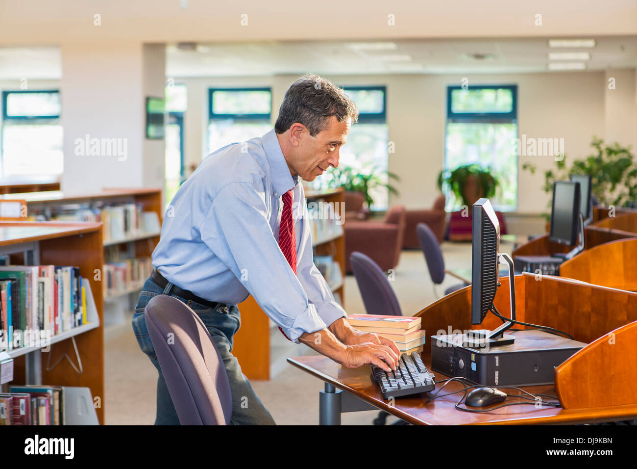 Ältere Mann arbeitet am Computer in der Bibliothek Stockfoto