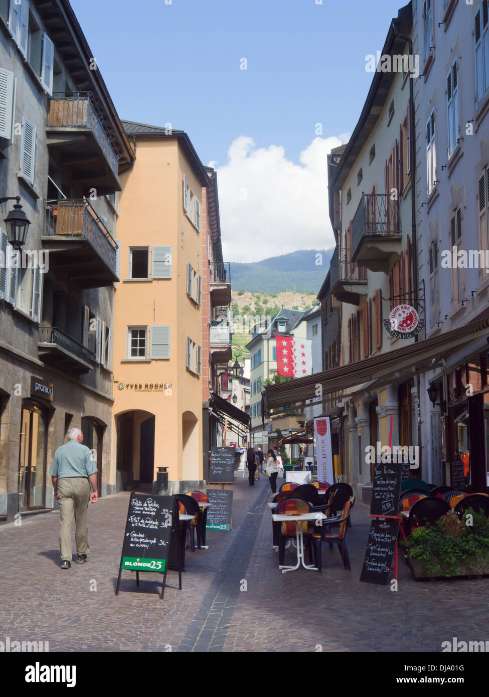 Fußgängerzone, Café mit Sitzgelegenheiten im Freien und Häuser in der Schweizer Stadt Sion Stockfoto