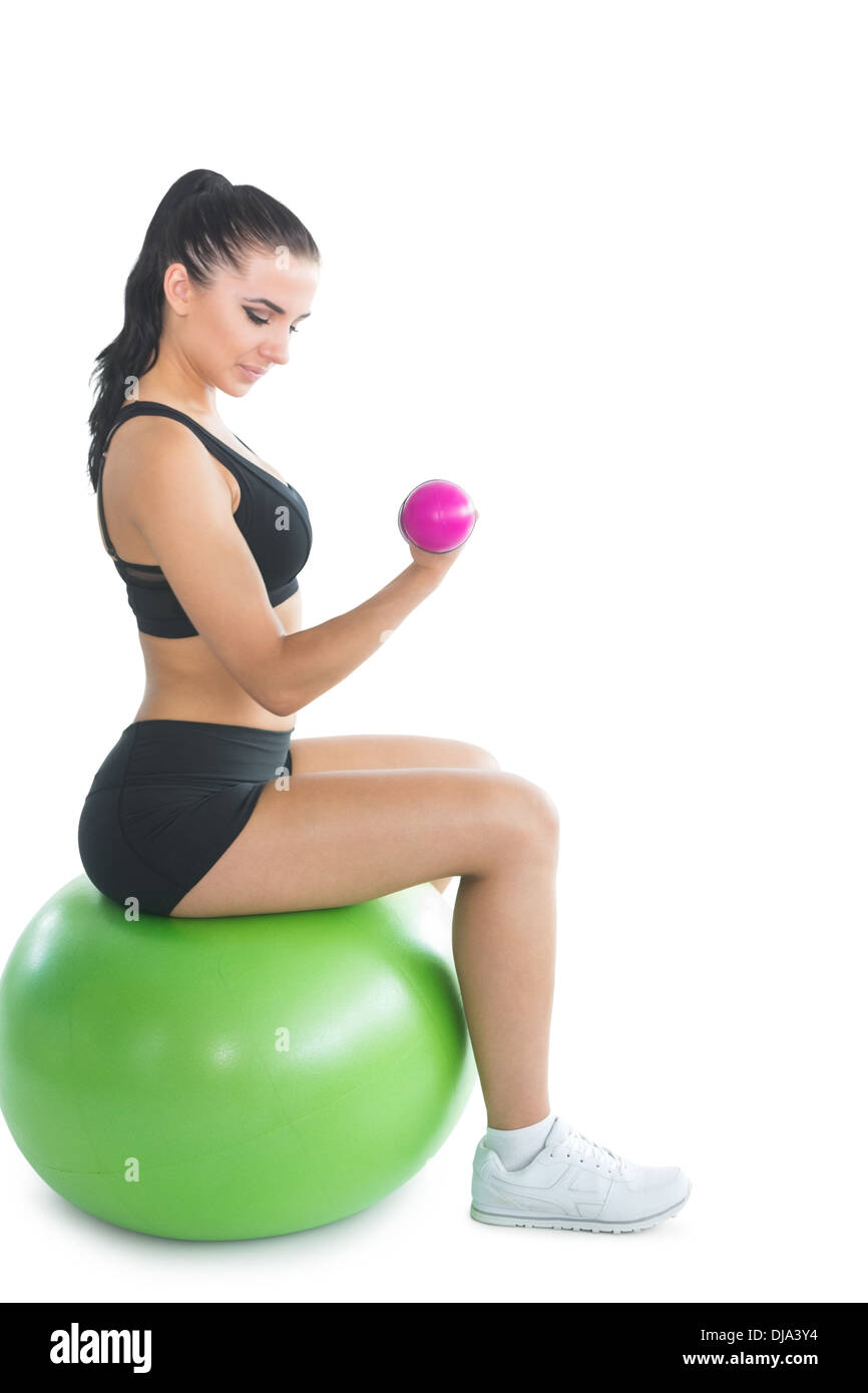 Attraktive junge Frau sitzen auf einem Gymnastikball mit rosa Hanteln Stockfoto