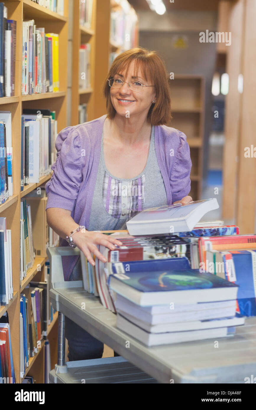 Weibliche Reife Bibliothekar wieder Bücher in der Bibliothek Stockfoto