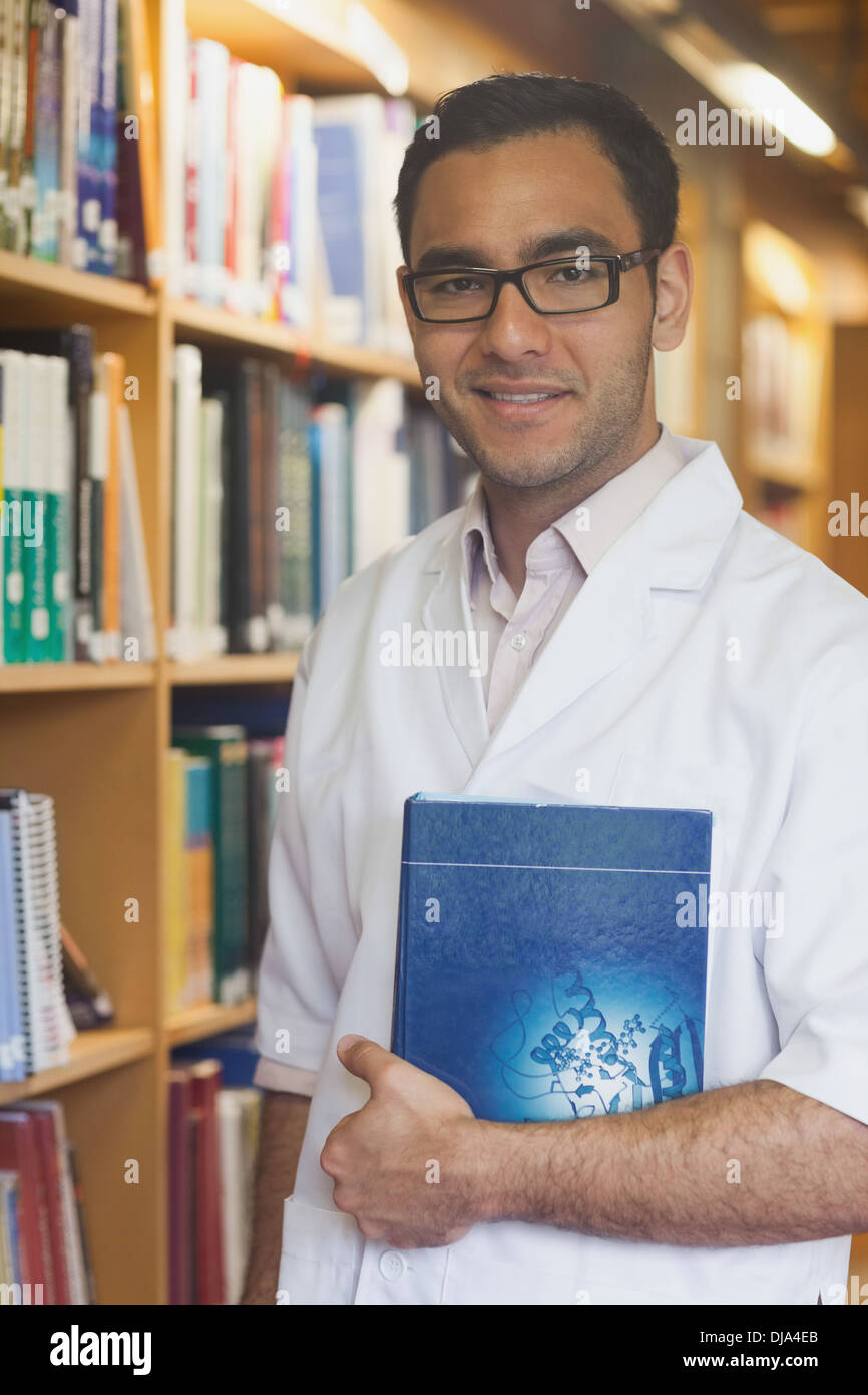 Attraktive intellektuellen Mann posiert in der Bibliothek ein Buch hält Stockfoto
