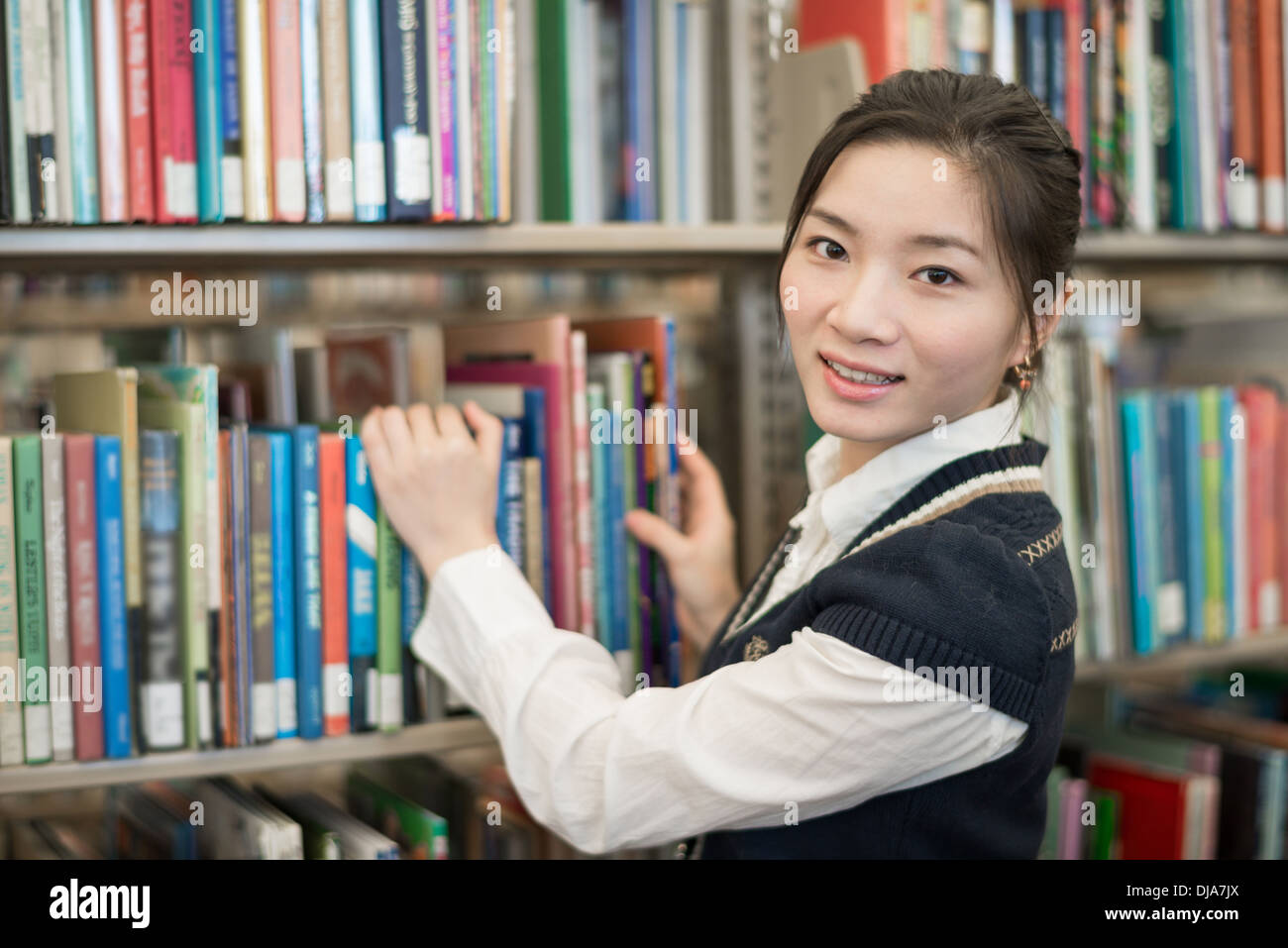 Porträt des jungen clevere Studenten steht man vor einem Bücherregal in Bibliothek Stockfoto