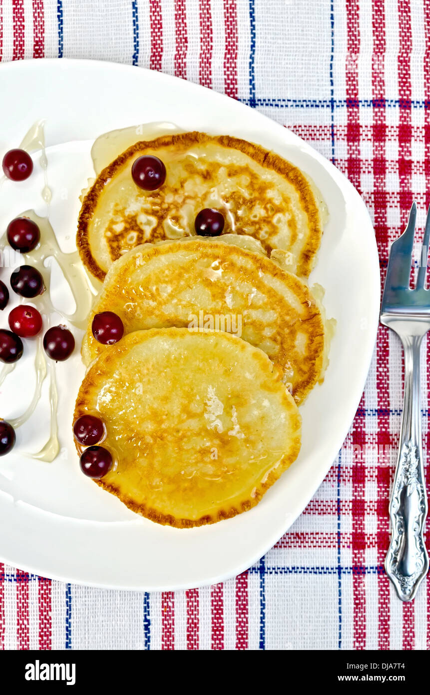 Pfannkuchen mit Preiselbeeren und Honig auf einem weißen Teller, Gabel auf Serviette Hintergrund Stockfoto