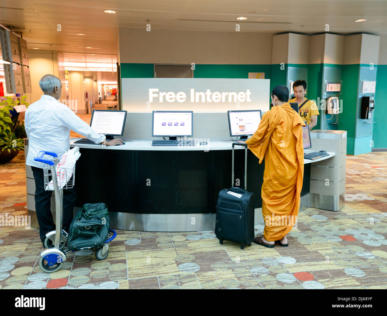 Moderne und traditionelle treffen sich in einem multikulturellen Umfeld: ein buddhistischer Mönch und indischer Geschäftsmann verwenden einen kostenlosen Internetzugang. Stockfoto