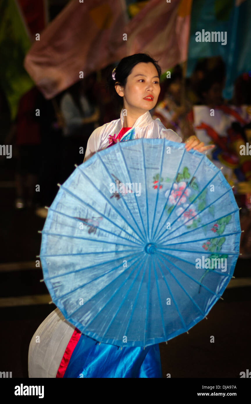 Frau tanzt mit einem ziemlich gemusterter Regenschirm in einer chinesischen Neujahr parade Stockfoto