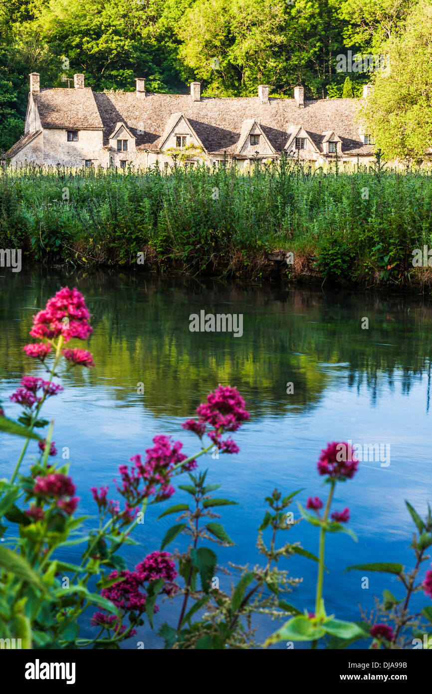 Blick über den Fluss Coln und Rack Isle Wasser Wiese zu den berühmten Arlington Row Cottages in Cotswold Dorf von Bibury. Stockfoto