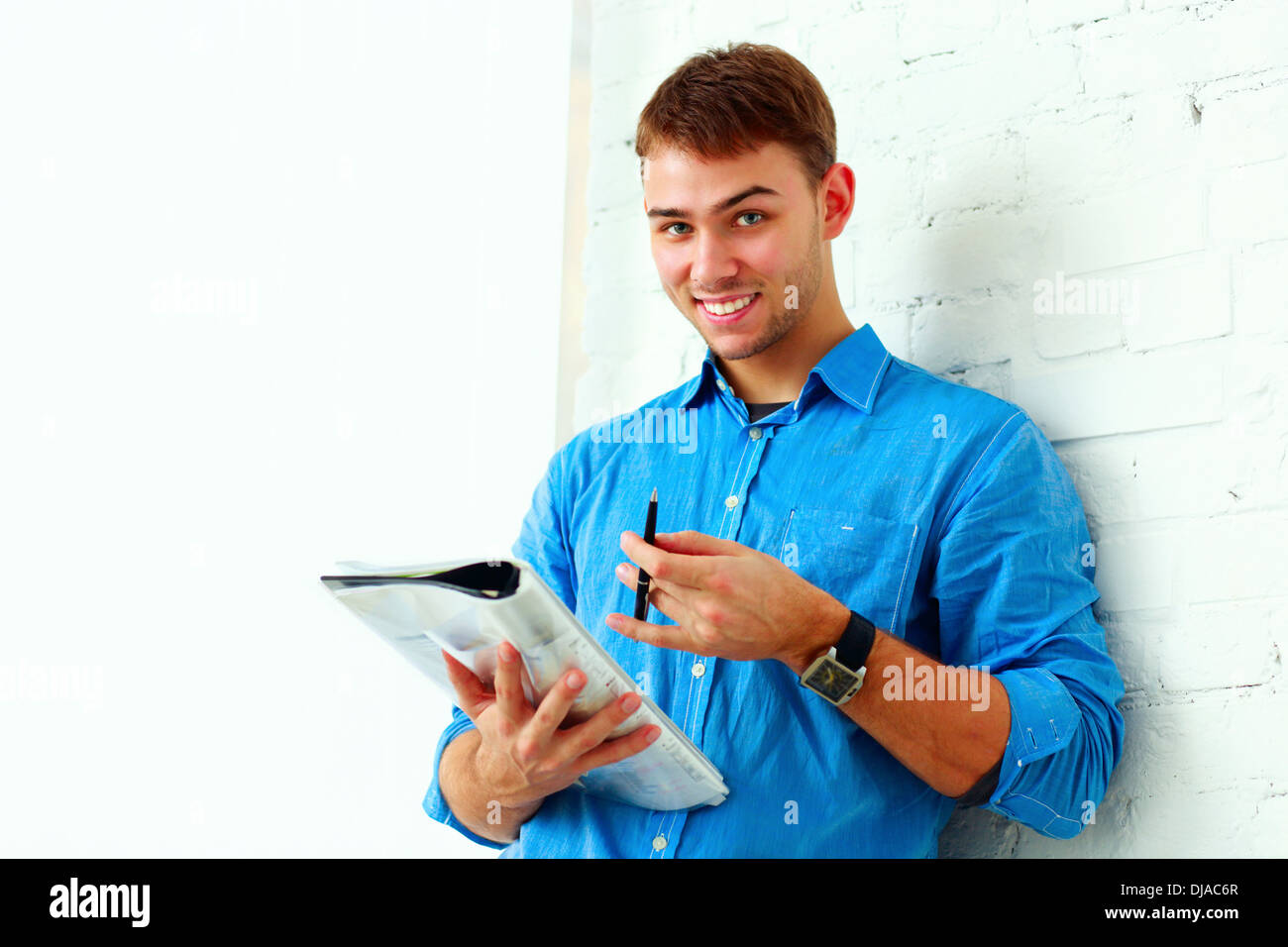 Glückliche Schüler mit Ordner in der Nähe der Wand stehend Stockfoto