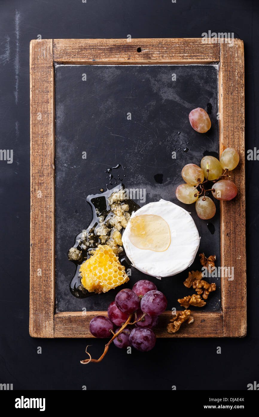 Käse mit Honig, Nüssen und Trauben an Vintage Schiefer Tafel Stockfoto