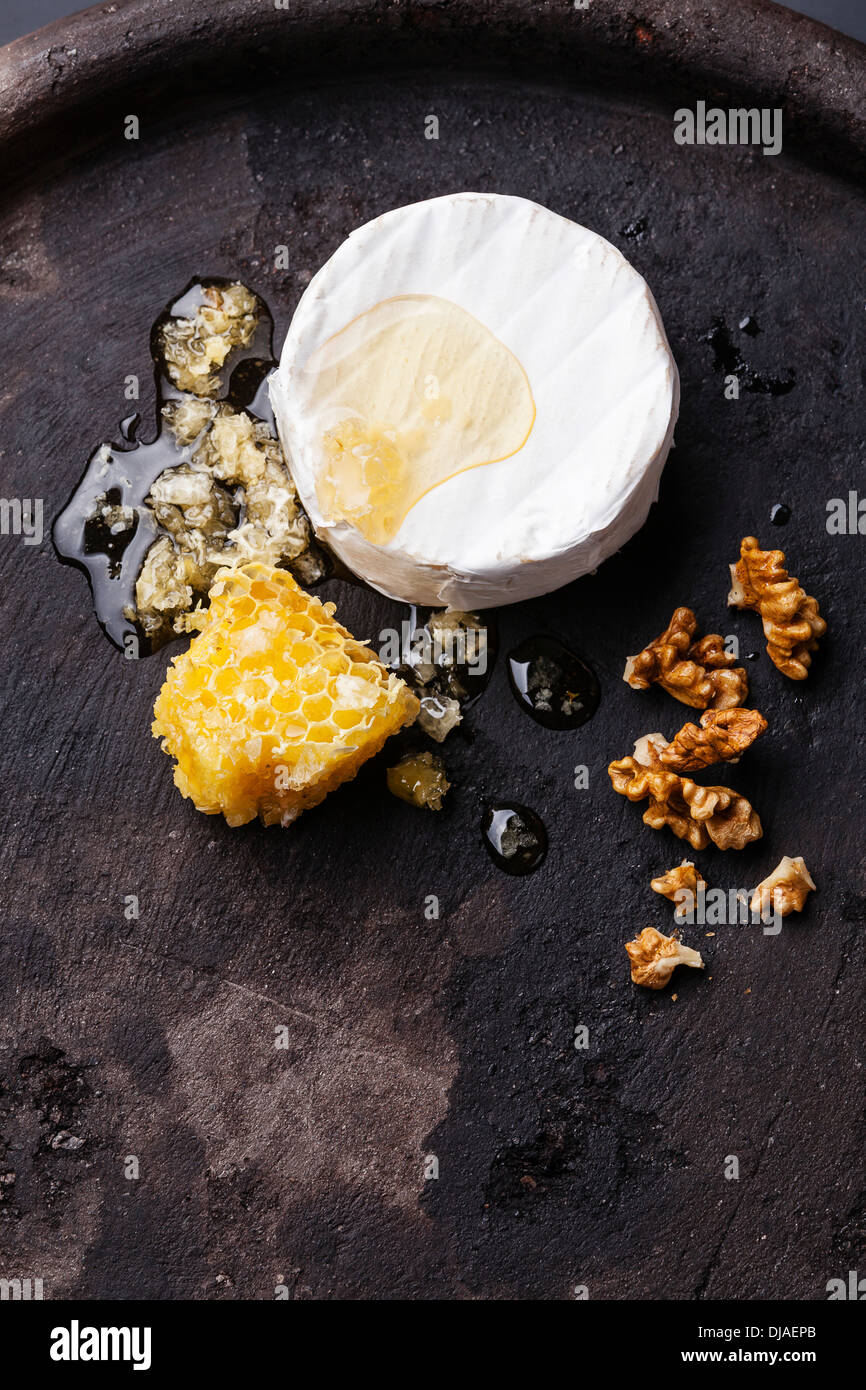 Käse mit Honig und Nüssen auf schwarz strukturierten Hintergrund Stockfoto