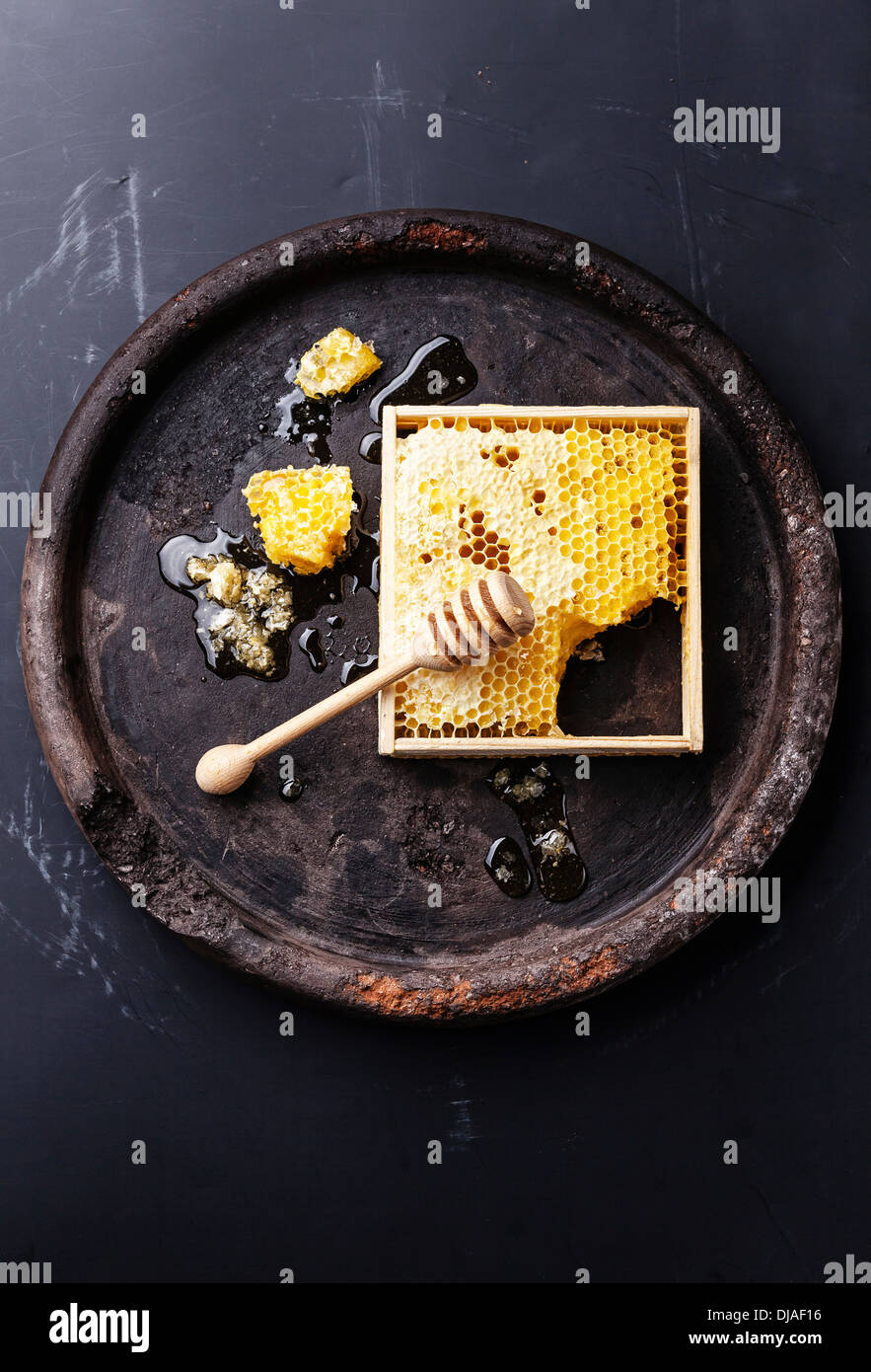 Waben Sie mit hölzernen Honig Dipper auf schwarz strukturierten Hintergrund Stockfoto