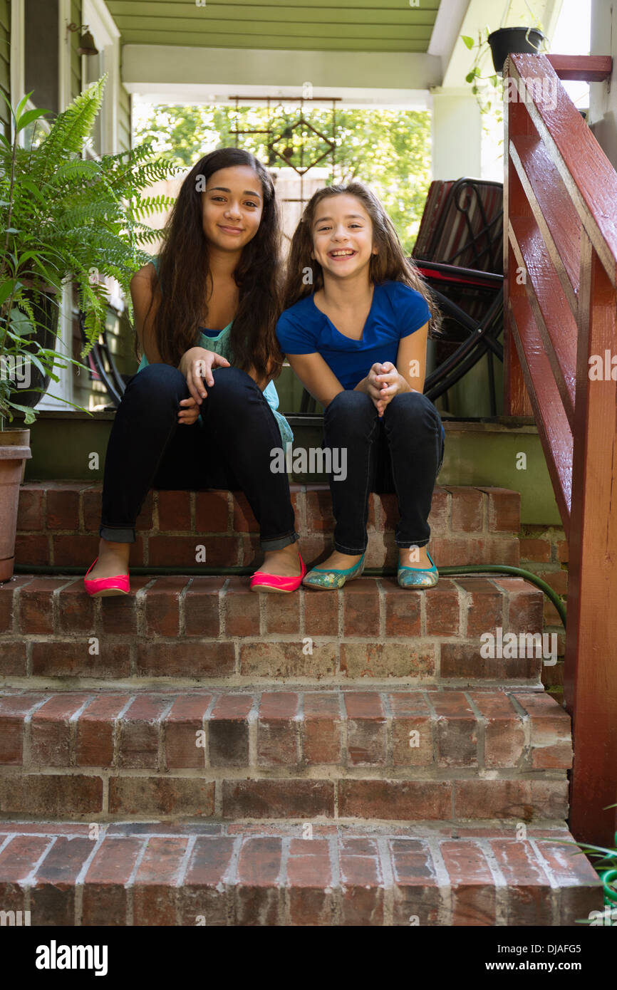 Gemischte Rassen Schwestern sitzen auf Stufen Stockfoto