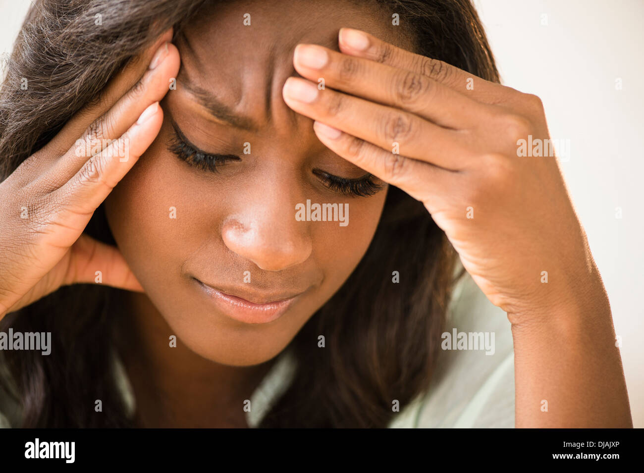 Schwarze Frau mit Kopf in Händen Stirnrunzeln Stockfoto