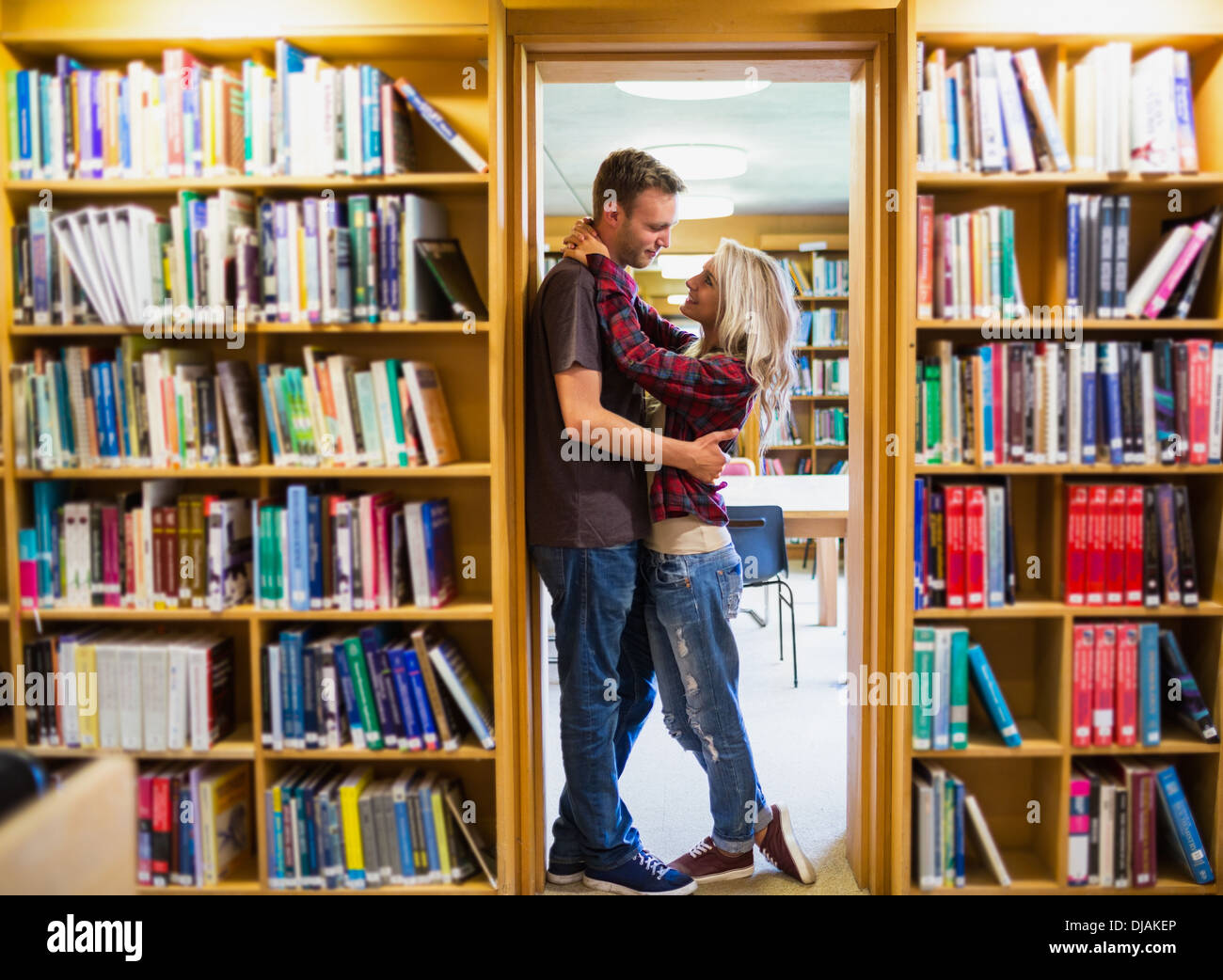 Romantisches Paar umarmt von Bücherregale in Bibliothek Stockfoto