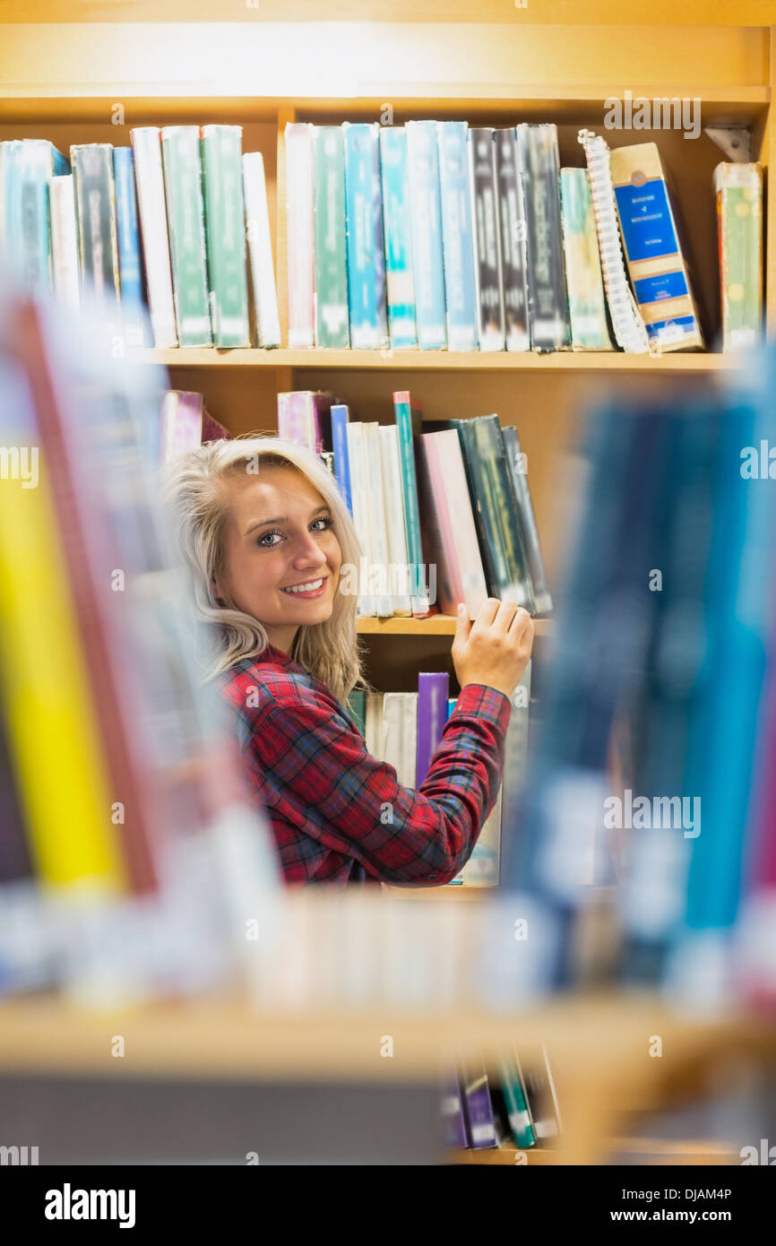 Lächelnde Frau inmitten Bücherregale in der Bibliothek Stockfoto