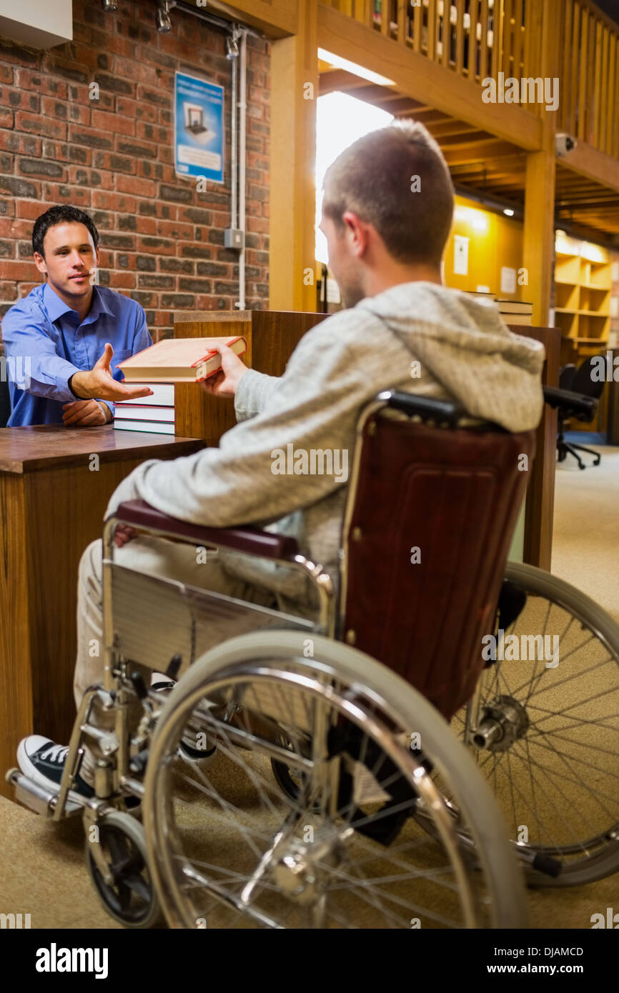 Student im Rollstuhl an der Bibliothek-Theke Stockfoto