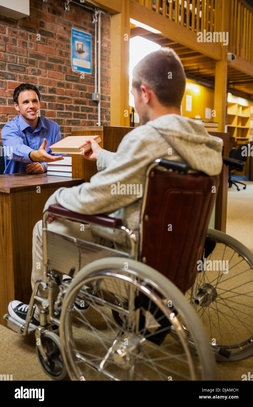 Student im Rollstuhl an der Bibliothek-Theke Stockfoto