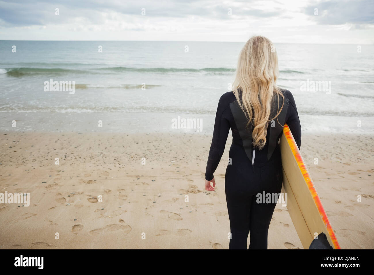 Rückansicht der Frau im Neoprenanzug mit Surfbrett am Strand Stockfoto