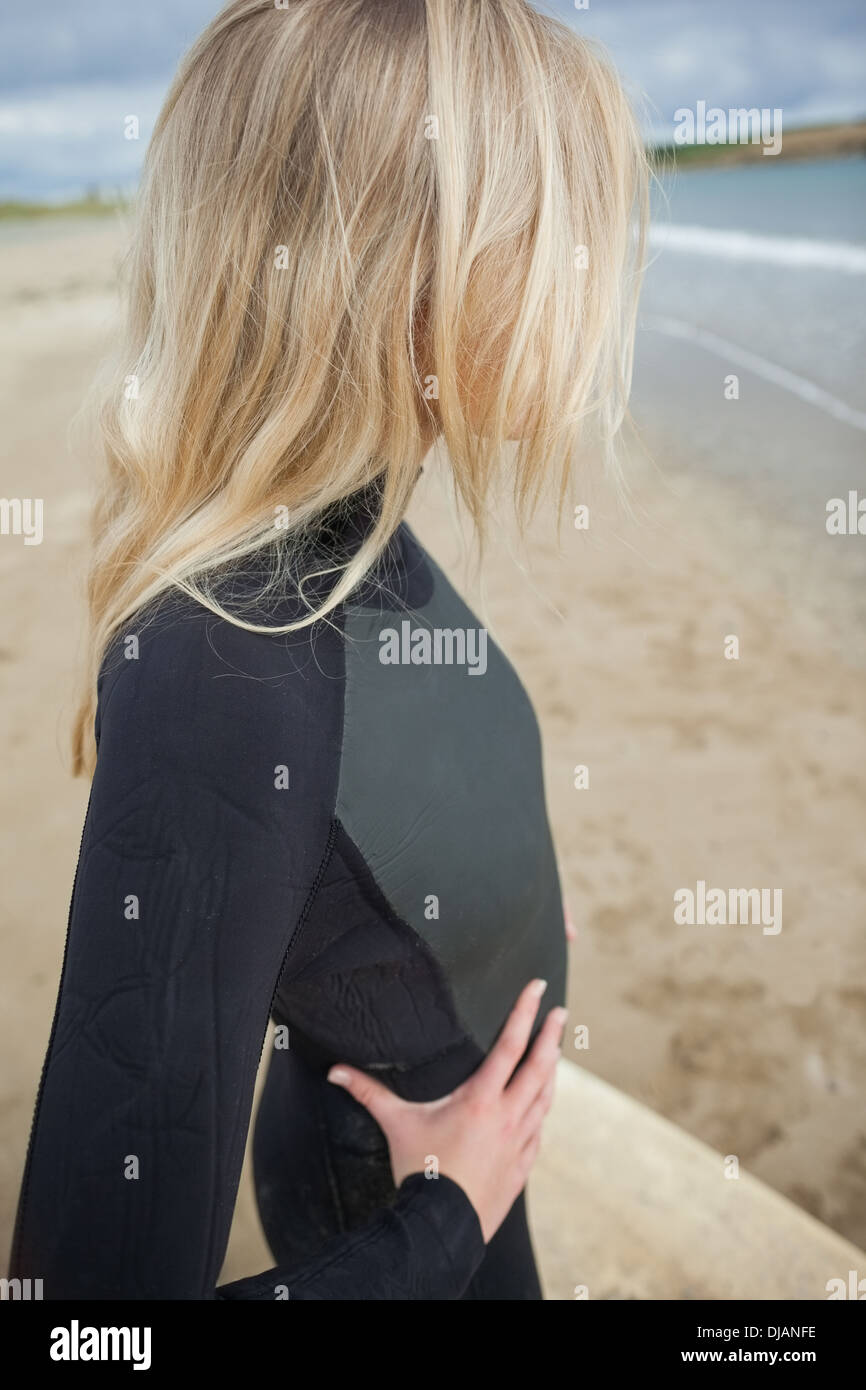 Schöne Blondine im Neoprenanzug am Strand Stockfoto