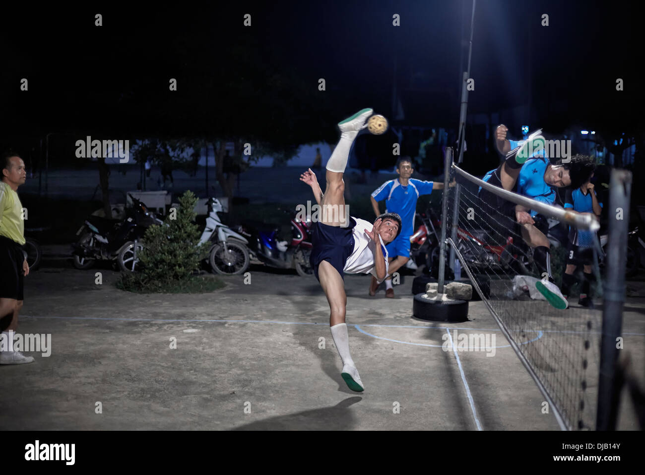 Extreme Sportlichkeit während eines nächtlichen Sepak Takraw. Traditionelle und beliebte thailändische Fußballspiel. S. E. Asien Thailand Stockfoto