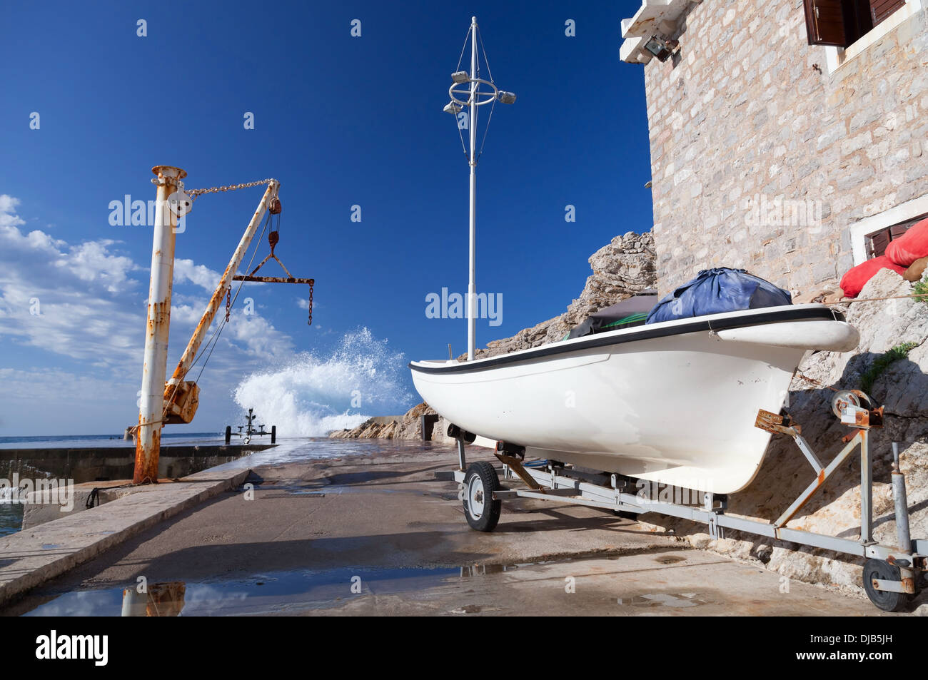 Weiße Fischerboot und kleinen Kran. Bahndamm der Stadt Petrovac, Montenegro Stockfoto