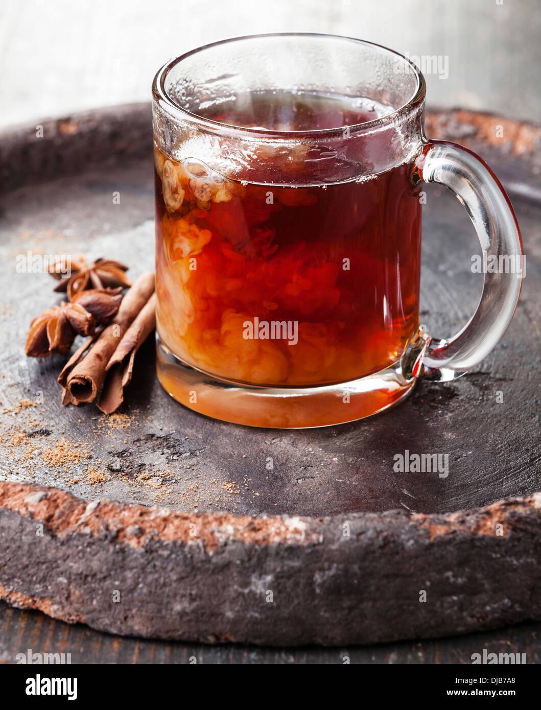 Heißen Tee mit Milch und Gewürzen auf dunklem Hintergrund Stockfoto