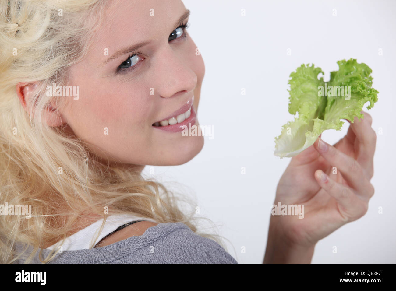 Attraktive blonde Frau mit Salatblatt Stockfoto