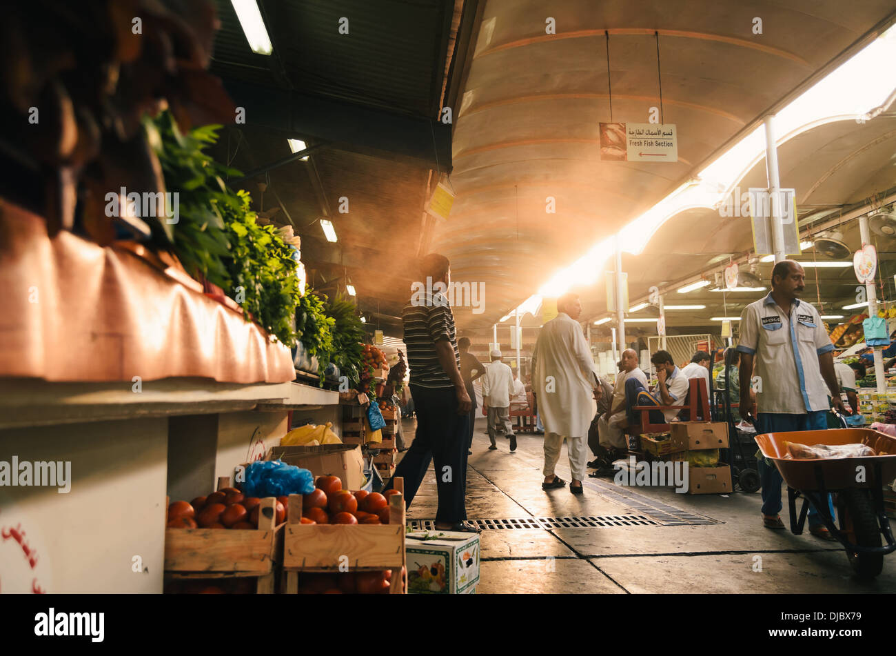 Arabische Männer zu Fuß entlang der Korridore in Deiras Obst- und Gemüsemarkt bei Sonnenaufgang. Dubai, Vereinigte Arabische Emirate. Stockfoto