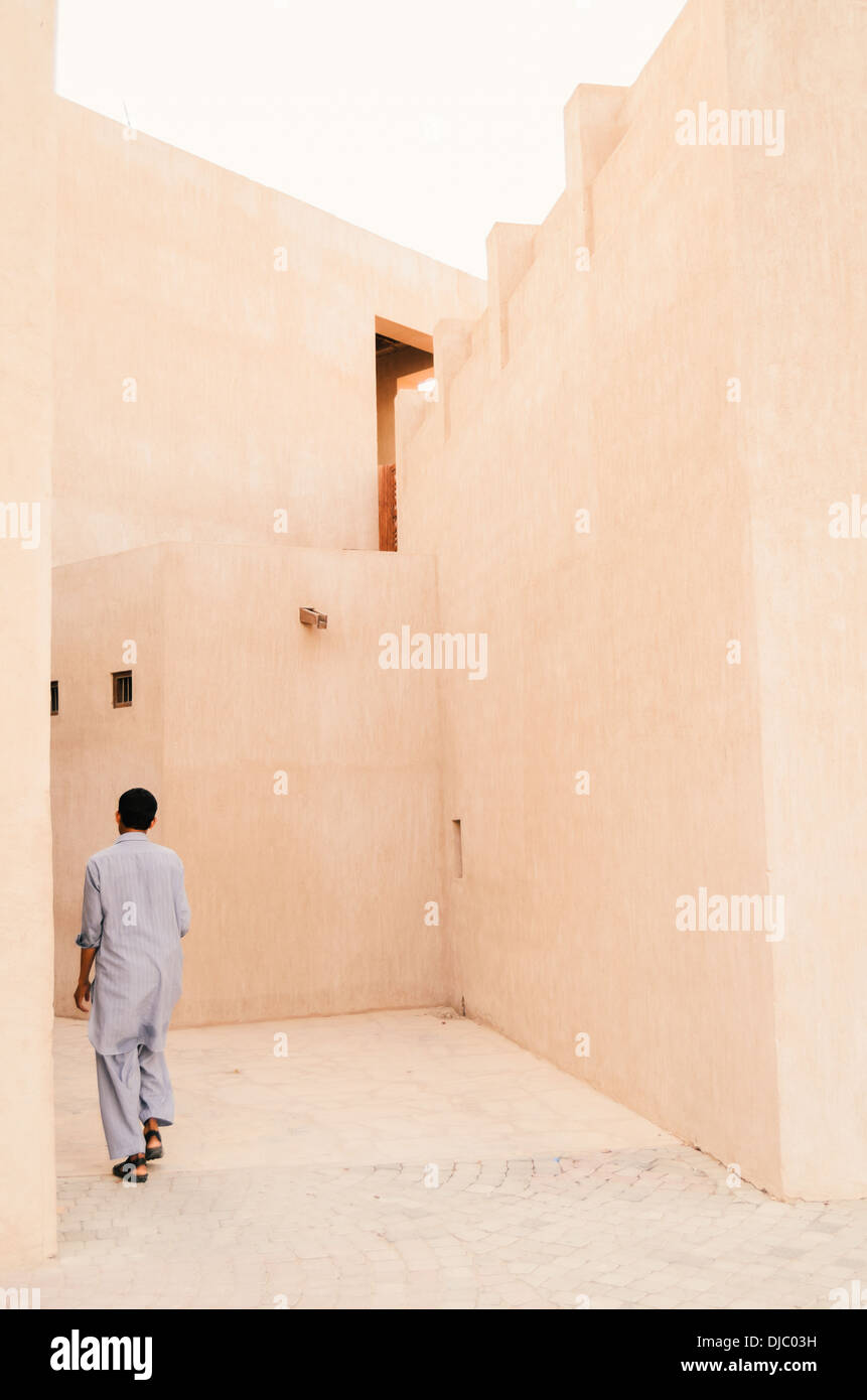 Muslimischen Mann zu Fuß durch die engen Straßen von Bastakiya Viertel im Stadtteil Al Fahidi historische. Dubai, Vereinigte Arabische Emirate. Stockfoto