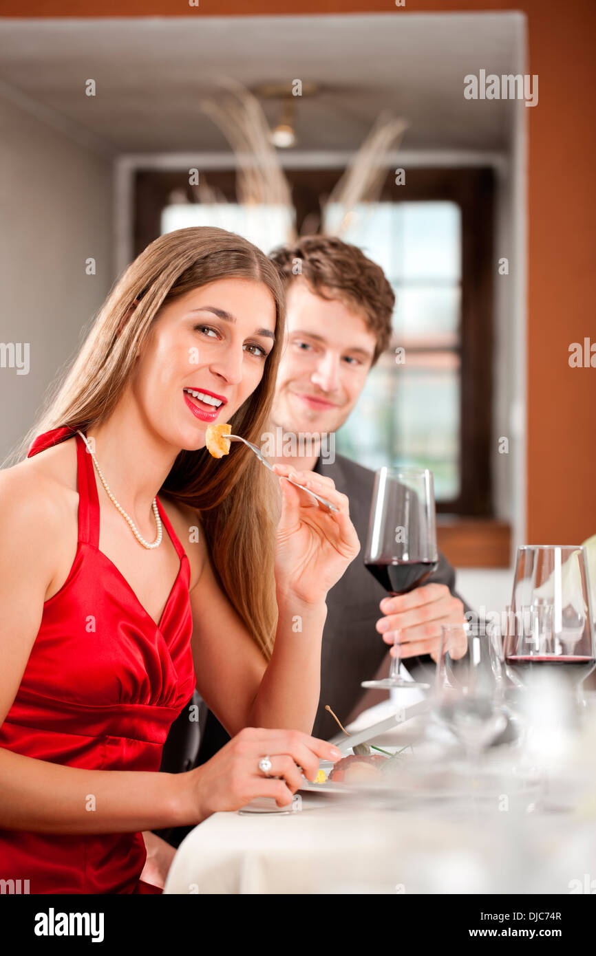 Porträt einer glücklichen Frau Essen mit Mann sitzt hinter Getränk Stockfoto