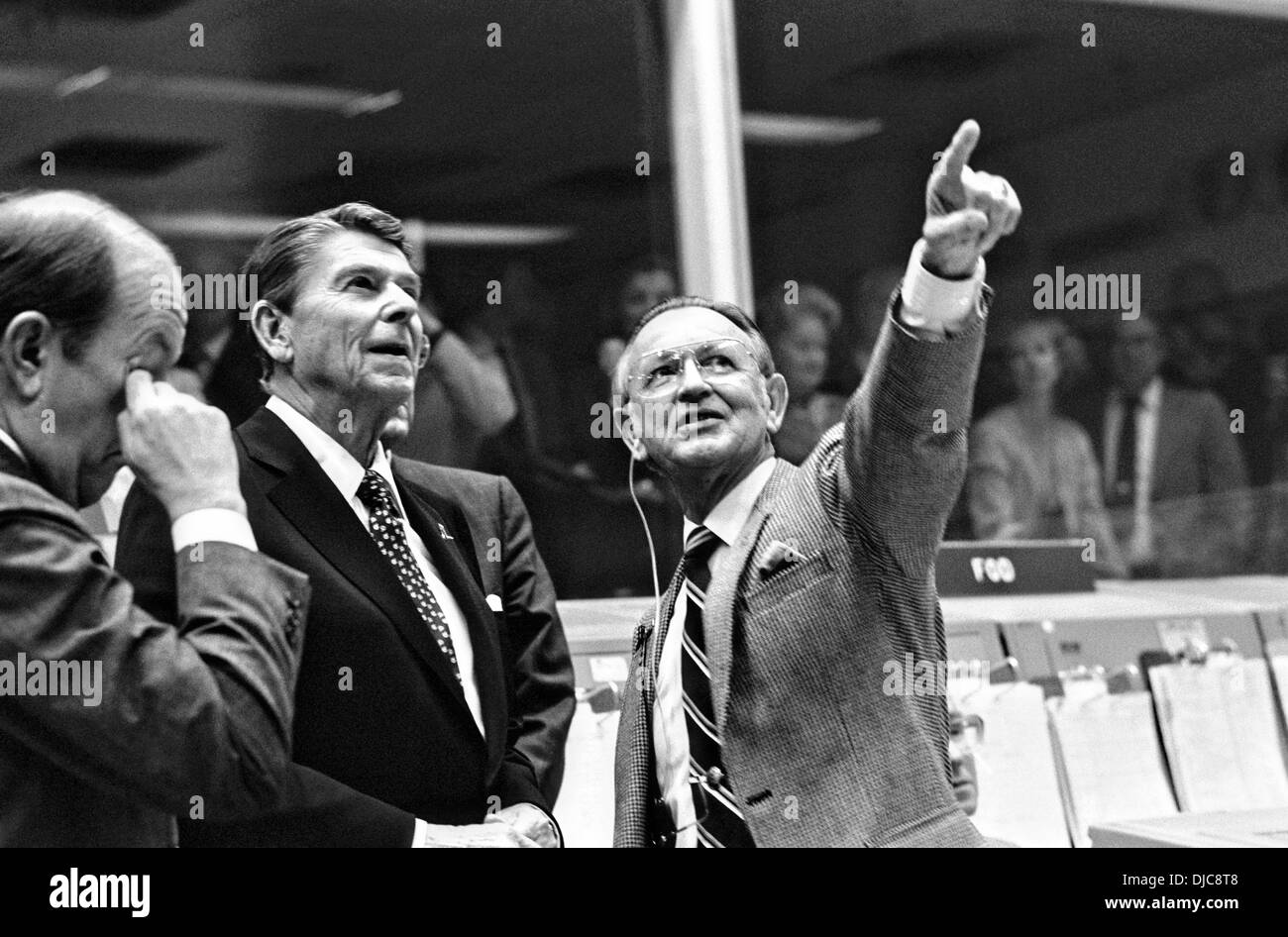 US-Präsident Ronald Reagan ist vom NASA JSC Direktor Christopher C. Kraft Jr., unterrichtet, die in Richtung der Orbiter Spotter auf dem Plotter Projektion an der Vorderseite der Sendung Operationen Leitwarte im Johnson Space Center der Mission Control Center 13. November 1986 in Houston, Texas zeigt. Dieses Bild entstand kurz vor einem Raum-zu-Boden-Gespräch zwischen STS-2 Crew-Mitglieder Joe H. Engle und Richard H. wirklich, die Erde in der Raumfähre Columbia umkreisen waren. Stockfoto