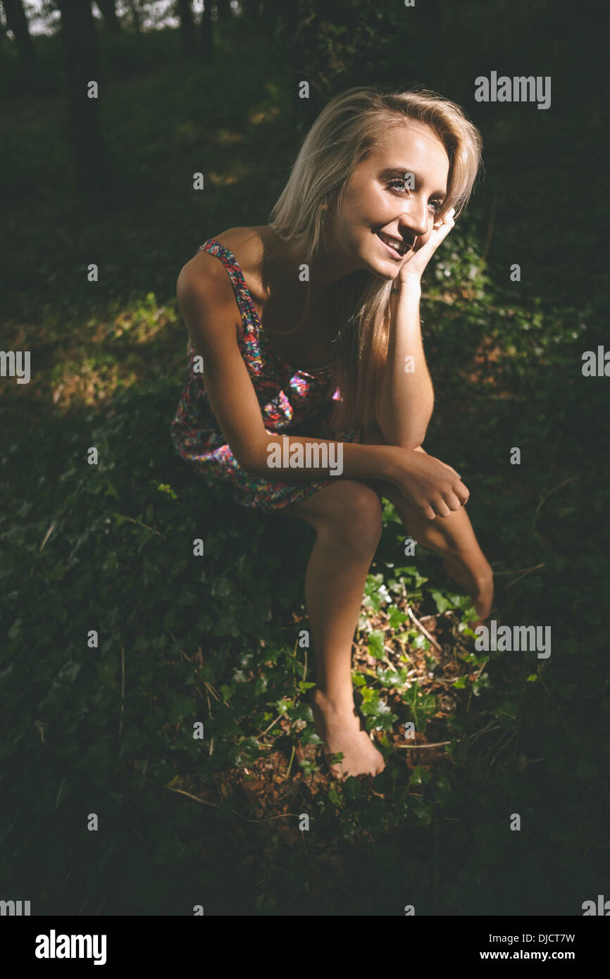 Lächelnd, wunderschöne Blondine sitzt auf dem Boden Stockfoto