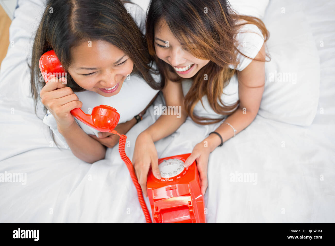 Zwei Schwestern tätigen eines Anrufs auf eine altmodische wählen Sie Telefon Stockfoto