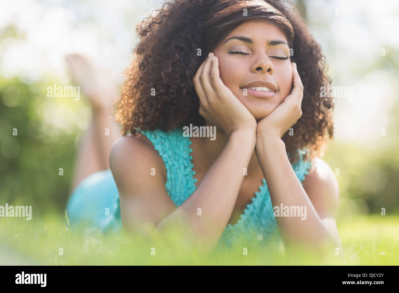 Wunderschöne ruhige Brünette auf Rasen liegend mit geschlossenen Augen Stockfoto
