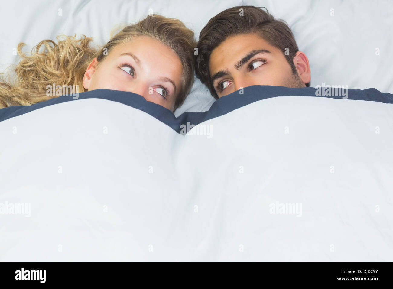 Schöne Frau versteckt unter einer Decke mit ihrem Freund Stockfoto