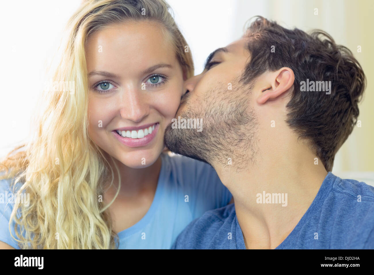 Blonde junge Frau wird von ihrem Freund auf die Wange geküsst Stockfoto