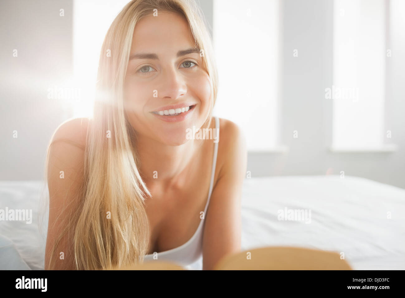 Fröhliche Blondine ein Buch auf ihrem Bett Stockfoto