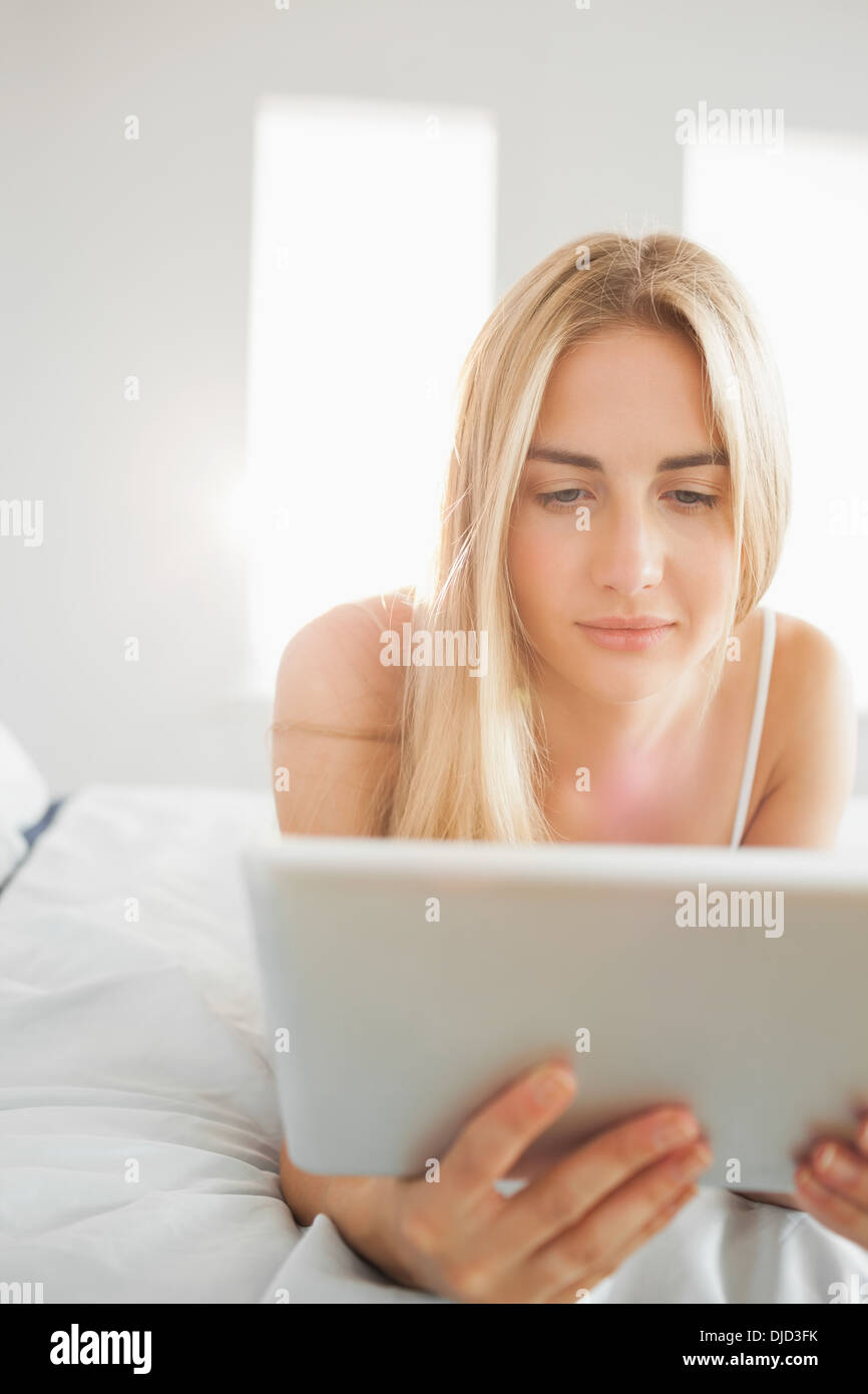 Hübsche Blondine mit digital-Tablette auf ihrem Bett Stockfoto