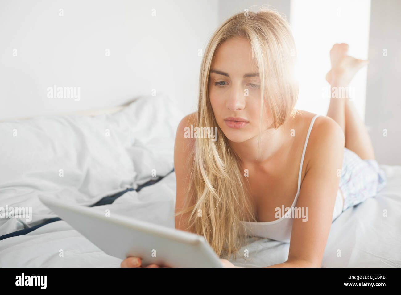 Ziemlich ruhig Blondine mit digital-Tablette auf ihrem Bett Stockfoto