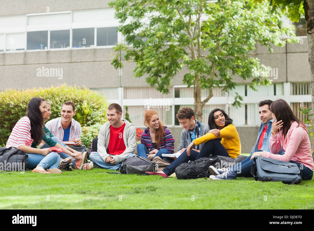 Gruppe von Studenten, die im Chat auf dem Rasen auf dem campus Stockfoto