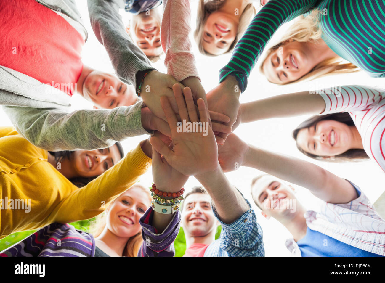 Gruppe von lächelnden Studenten setzen Hände in einem Kreis auf dem campus Stockfoto