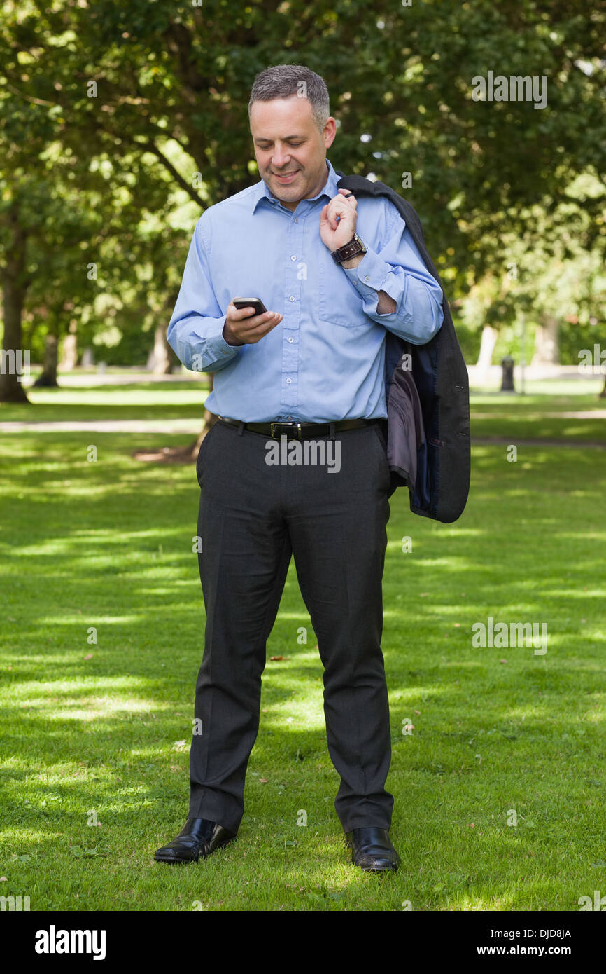 Glücklich Professor stehend auf dem Campus SMS auf dem Handy Stockfoto