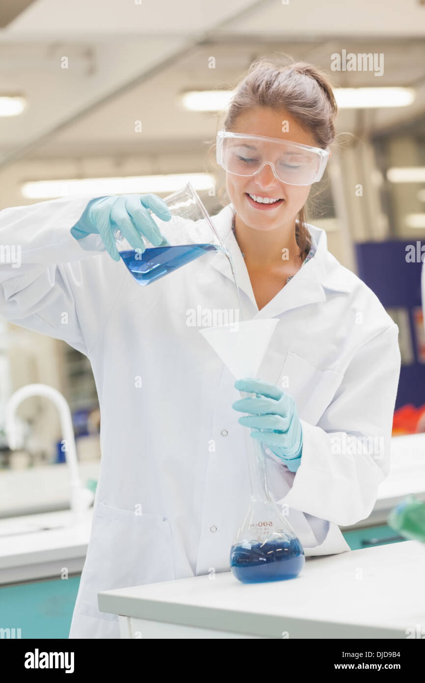 Lächelnde Student Gießen blaue Flüssigkeit in den Trichter Stockfoto
