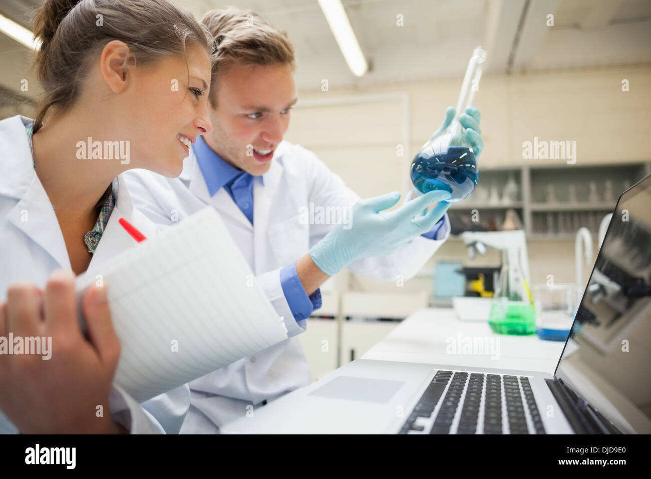 Zwei lächelnde Studenten Blick auf blaue Flüssigkeit und unter Notizen Stockfoto