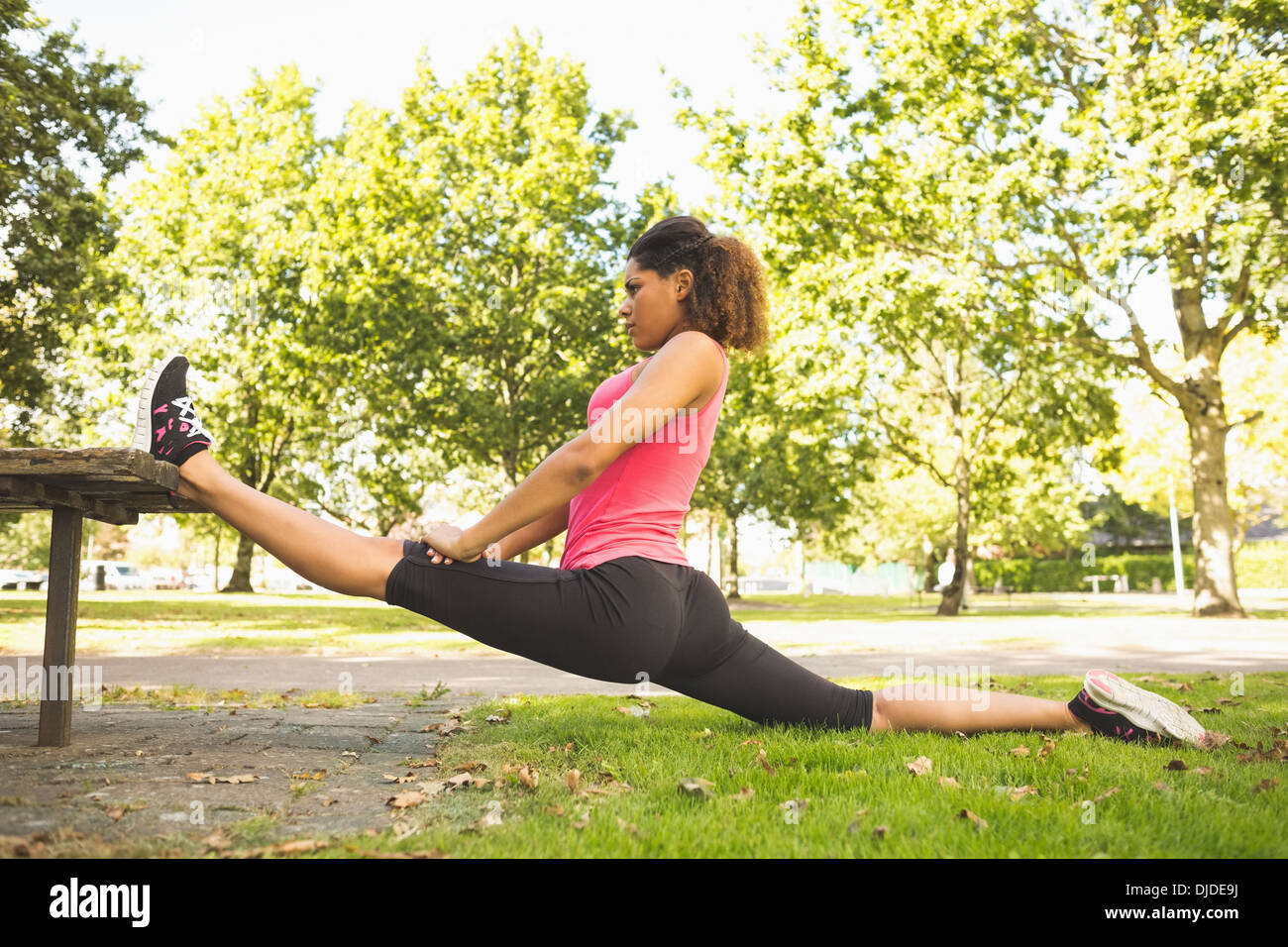 Flexible junge Frau, die den Spagat trainieren im park Stockfoto