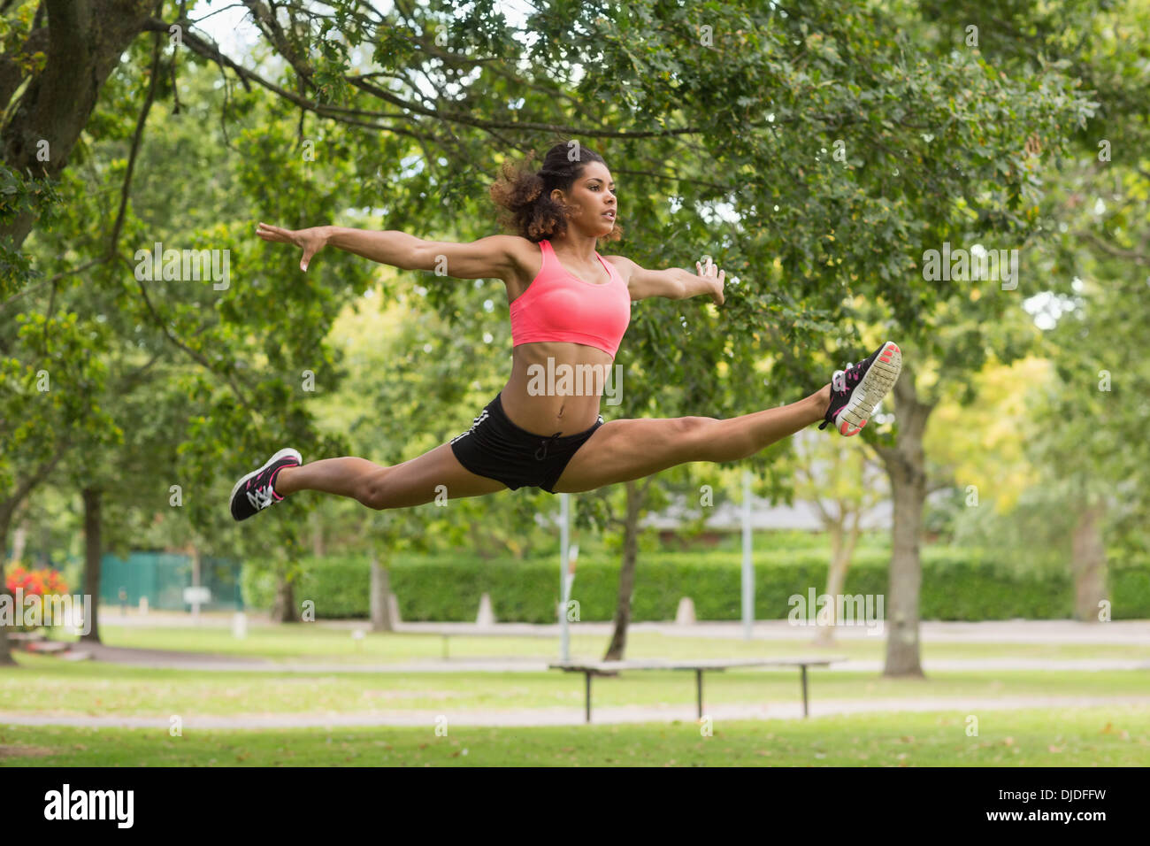 Durchtrainierte Frau Durchführung den Spagat springen im park Stockfoto